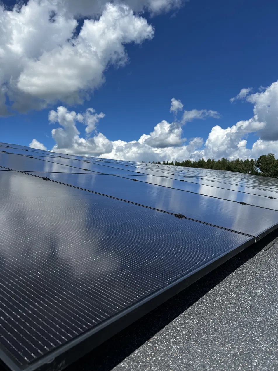 Solpaneler sedda underifrån mot en blå himmel med moln.