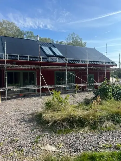 Nybyggt hus med byggnadsställning där solpaneler monteras samtidigt som taket färdigställs.