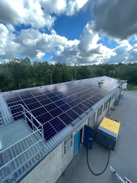 Industribyggnad med solpaneler på taket sedd från marknivå.