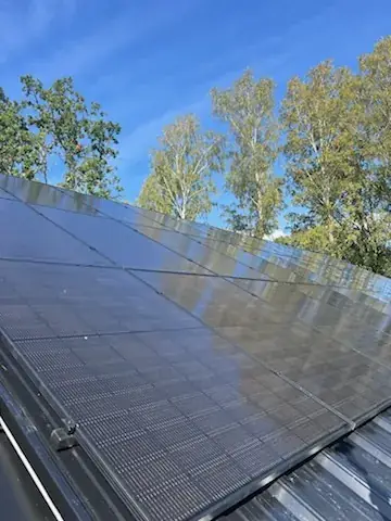 Uppvinklade solpanelrader på ett platt tak under klar himmel.